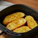 Crispy frozen garlic bread in an air fryer basket.