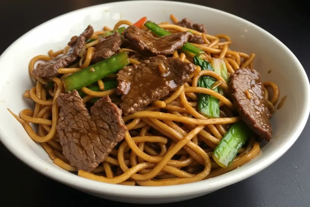 A steaming bowl of Mongolian beef noodles with beef, noodles, and sesame seeds